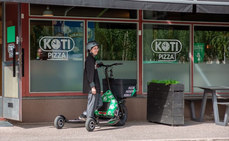 Kotipizza aloittaa pilotoimaan sähköpotkukelkkojen käyttöä pizzojen kotiinkuljetuksissa. Kuvassa Kotipizzatyöntekijä Aino. 